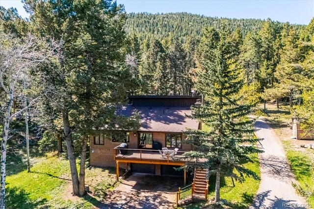25357 Snyder Ave, Conifer, CO 80433 - rear view of property featuring a wooded view, a deck, driveway, and brick siding