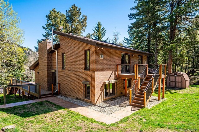 25357 Snyder Ave, Conifer, CO 80433 - rear view of property with a shed, stairway, a deck, an outdoor structure, and a chimney