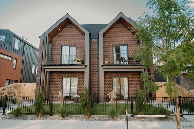 view of front of property featuring a fenced front yard, a balcony, and brick siding