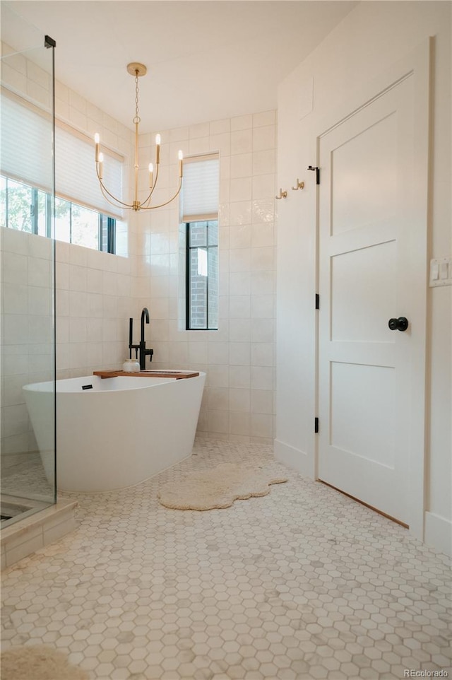 full bathroom featuring a tile shower, an inviting chandelier, a freestanding tub, tile patterned floors, and tile walls