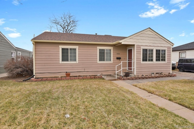 view of front of house featuring a shingled roof and a front yard