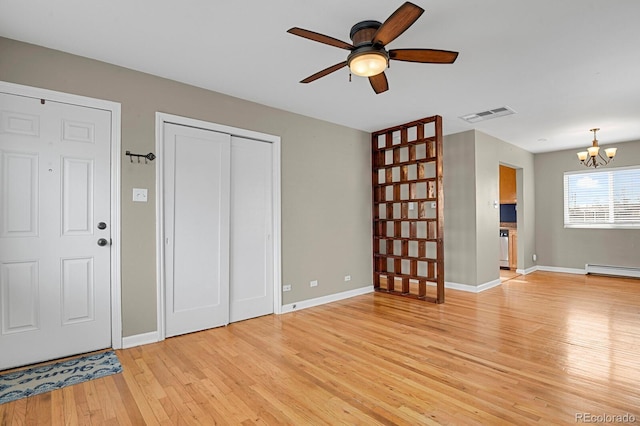 interior space featuring visible vents, ceiling fan with notable chandelier, light wood-style flooring, and baseboards