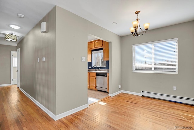 interior space featuring light wood finished floors, baseboards, dishwasher, baseboard heating, and a sink