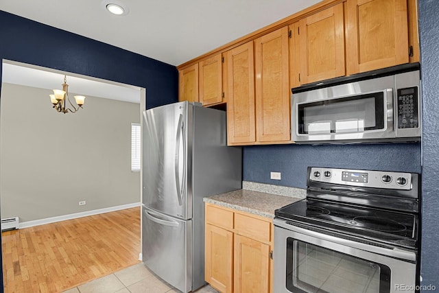 kitchen with light tile patterned floors, baseboards, stainless steel appliances, light countertops, and a chandelier