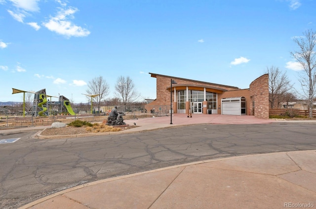 exterior space with a playground, driveway, and fence