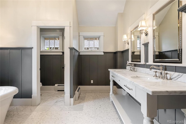 4535 E Montview Blvd, Denver, CO 80207 - bathroom featuring wainscoting, vaulted ceiling, baseboard heating, plenty of natural light, and double vanity