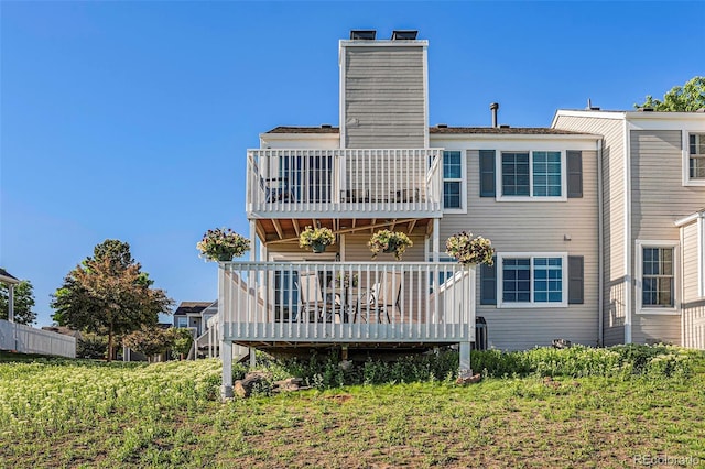 back of property featuring a balcony and a chimney