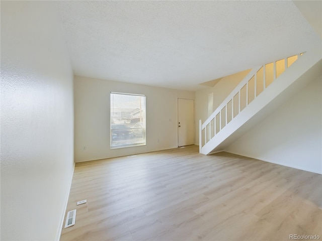 unfurnished living room with a textured ceiling and light hardwood / wood-style flooring