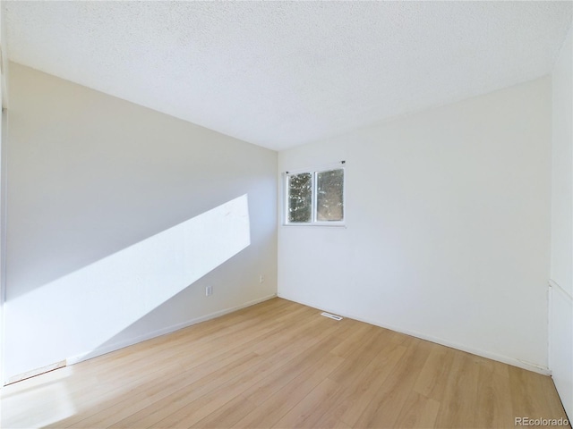 unfurnished room featuring a textured ceiling and light hardwood / wood-style flooring