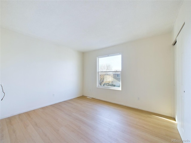 unfurnished room featuring a textured ceiling and light hardwood / wood-style flooring