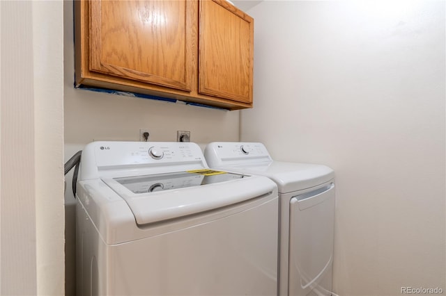 washroom featuring cabinets and washing machine and clothes dryer