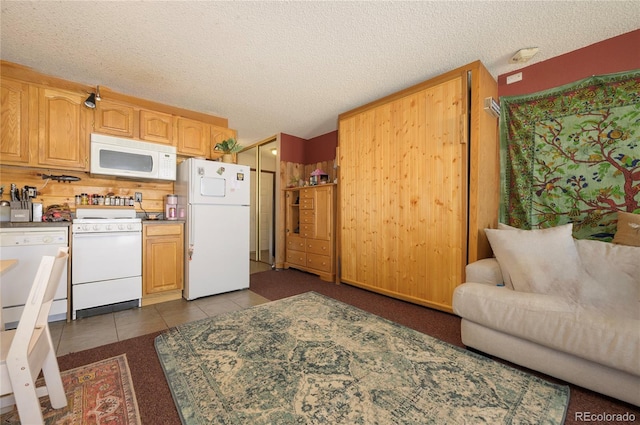 kitchen with a textured ceiling, white appliances, and dark tile patterned flooring