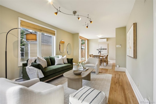 living area featuring light wood-type flooring, baseboards, and a wall mounted AC