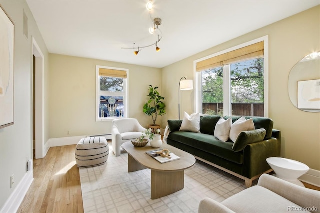 living room with light wood-style flooring, baseboards, and a baseboard heating unit