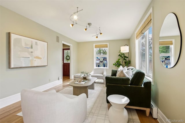 living area featuring baseboards, a baseboard radiator, and light wood-style floors