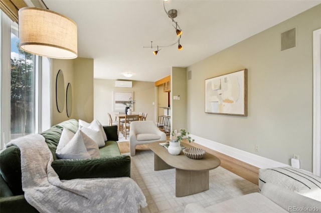 living area with a wall unit AC, wood finished floors, and baseboards