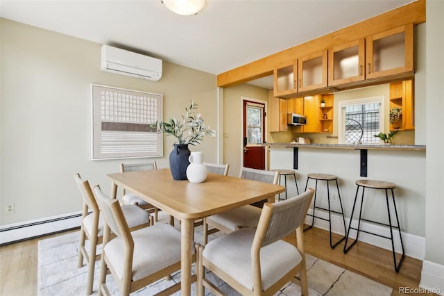 dining space with an AC wall unit, plenty of natural light, and light wood-type flooring