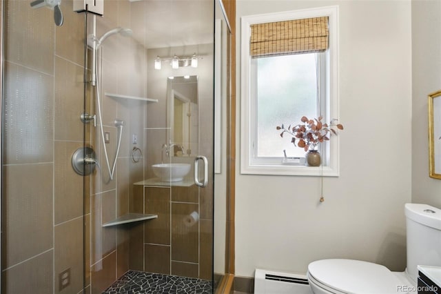 full bathroom with a baseboard radiator, a sink, a shower stall, toilet, and healthy amount of natural light