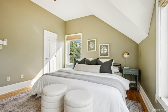 bedroom featuring wood finished floors, lofted ceiling, and baseboards