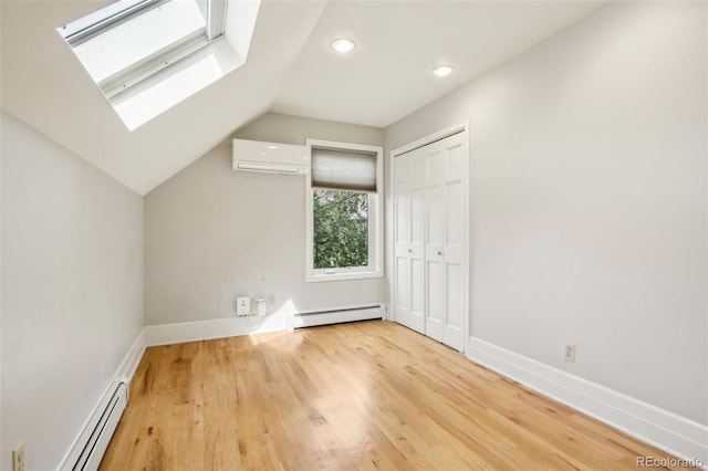 bonus room with a wall unit AC, a baseboard heating unit, a skylight, vaulted ceiling, and wood finished floors