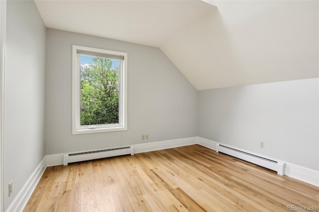 bonus room with baseboard heating, light wood-type flooring, lofted ceiling, and baseboards