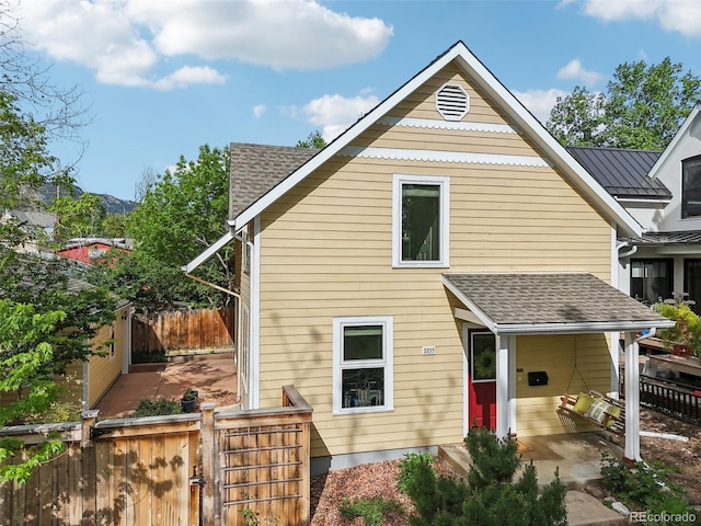 rear view of house featuring a gate and a shingled roof