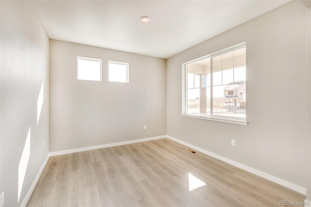 unfurnished room featuring light wood-type flooring and a healthy amount of sunlight