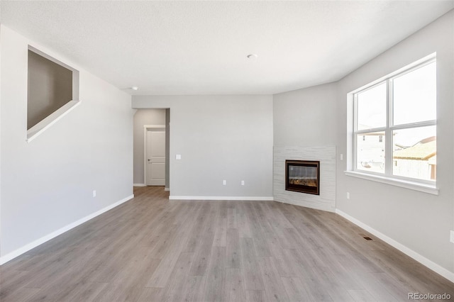 unfurnished living room featuring light wood-type flooring and a textured ceiling