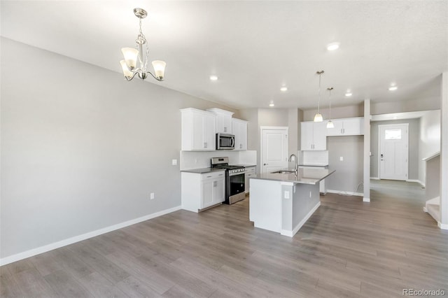 kitchen featuring hanging light fixtures, a center island with sink, white cabinets, appliances with stainless steel finishes, and sink