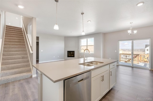 kitchen featuring sink, white cabinets, dishwasher, a center island with sink, and pendant lighting