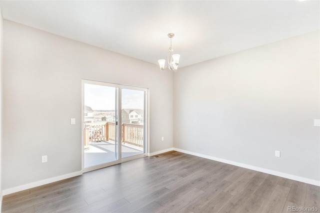 empty room featuring a notable chandelier and hardwood / wood-style floors