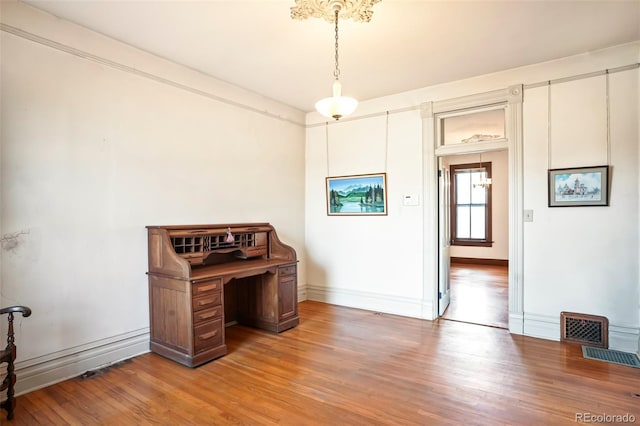 office featuring baseboards, visible vents, and wood finished floors