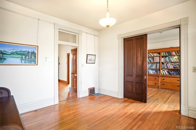 unfurnished bedroom with visible vents, light wood-style flooring, and baseboards