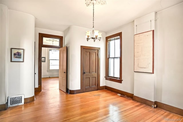 entryway featuring baseboards, visible vents, a notable chandelier, and light wood finished floors