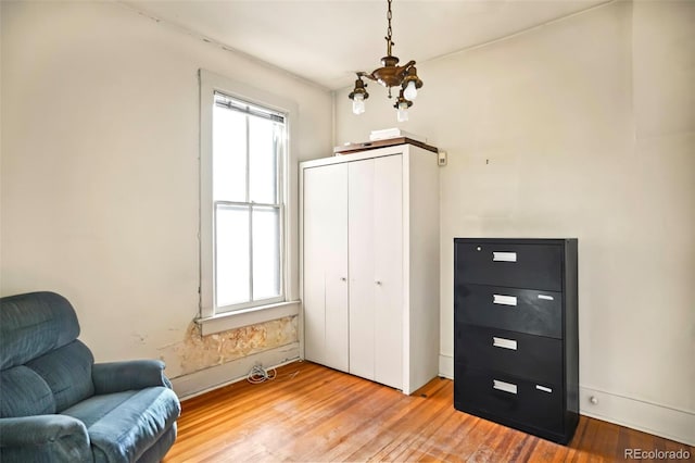 sitting room with light wood finished floors, baseboards, and an inviting chandelier