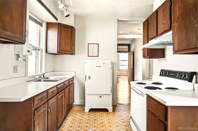 kitchen featuring under cabinet range hood, white electric range, a sink, water heater, and light countertops