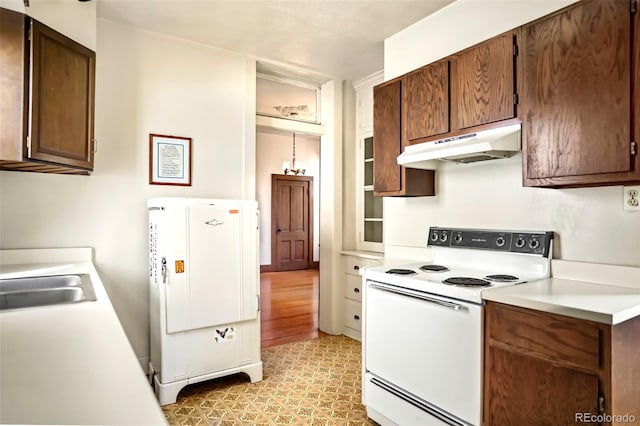 kitchen featuring light countertops, white appliances, a sink, and under cabinet range hood