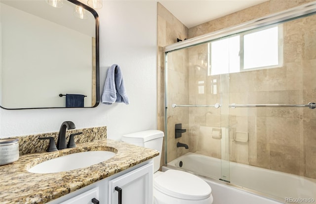 full bathroom featuring combined bath / shower with glass door, vanity, and toilet