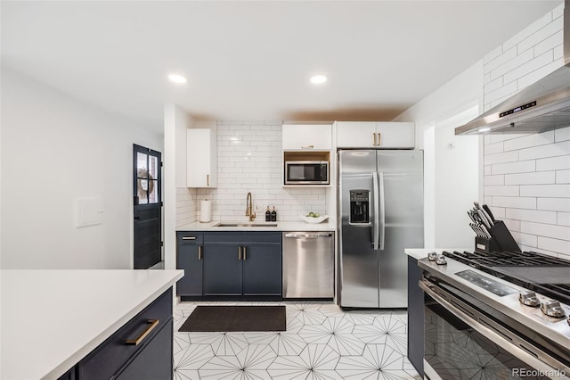 kitchen with sink, wall chimney range hood, white cabinetry, stainless steel appliances, and tasteful backsplash