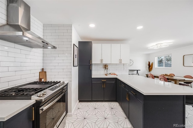 kitchen with stainless steel gas stove, ventilation hood, a kitchen breakfast bar, kitchen peninsula, and white cabinets