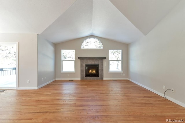 27627 E Broadview Dr, Kiowa, CO 80117 - unfurnished living room featuring vaulted ceiling, light wood-style flooring, a tiled fireplace, healthy amount of natural light, and baseboards