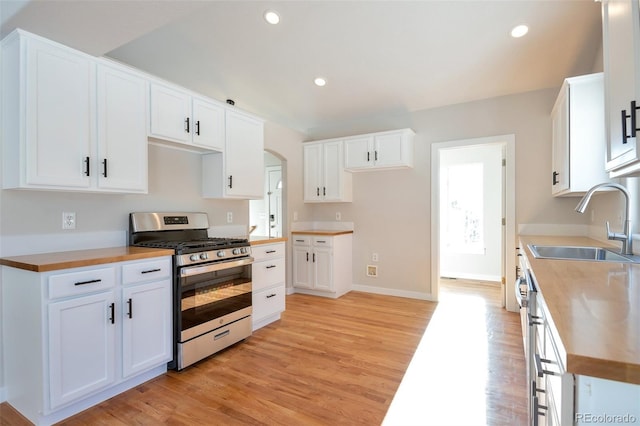 27627 E Broadview Dr, Kiowa, CO 80117 - kitchen with stainless steel gas range oven, a sink, arched walkways, light wood-type flooring, and white cabinetry
