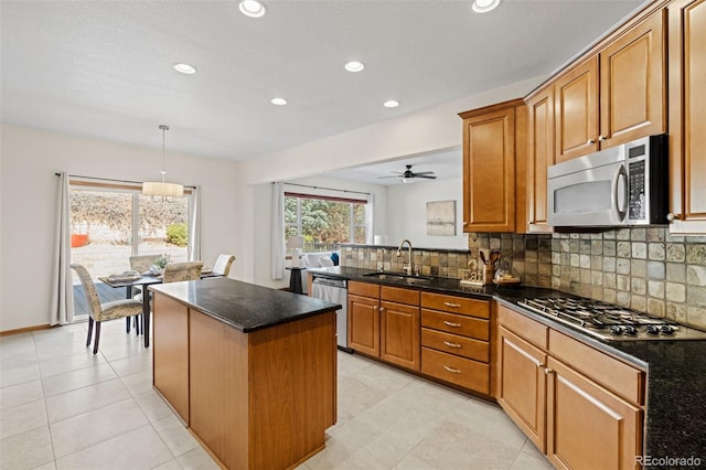 kitchen featuring tasteful backsplash, appliances with stainless steel finishes, brown cabinetry, and a sink