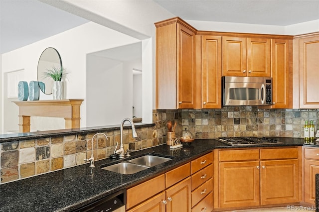 kitchen featuring stainless steel appliances, tasteful backsplash, brown cabinetry, a sink, and dark stone countertops