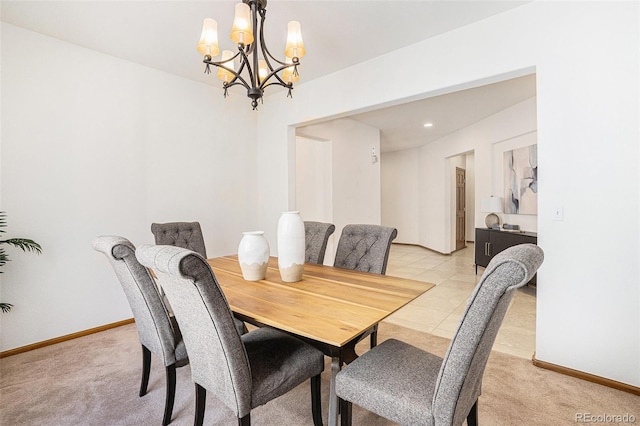 dining space featuring light carpet, baseboards, and a chandelier