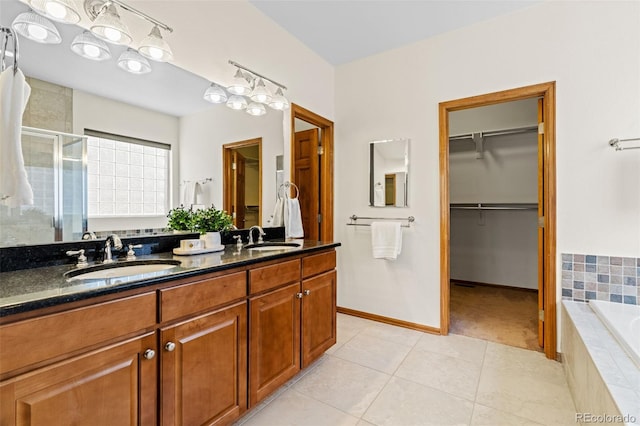 full bathroom featuring a stall shower, a spacious closet, a sink, and tile patterned floors