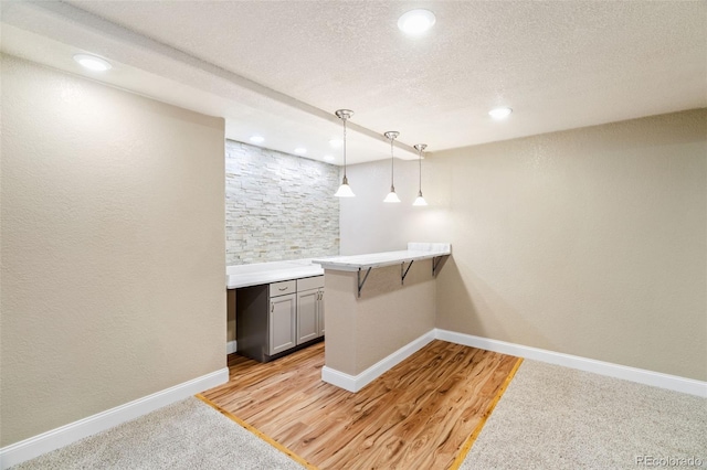 laundry room featuring light wood-style floors, recessed lighting, a textured ceiling, and baseboards