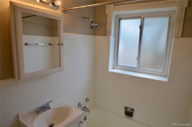 bathroom with tile walls, vanity, and tiled shower / bath