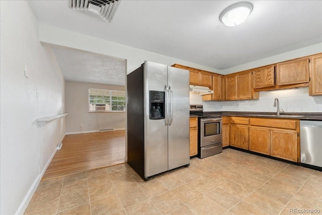 6721 Quay Ct, Arvada, CO 80003 - kitchen with stainless steel appliances, under cabinet range hood, dark countertops, brown cabinetry, and cooling unit
