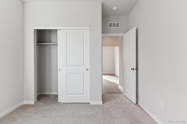 unfurnished bedroom with light colored carpet and a closet